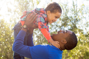 Father holding toddler son in air
