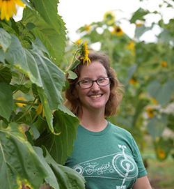 Woman smiling standing next to sunflower