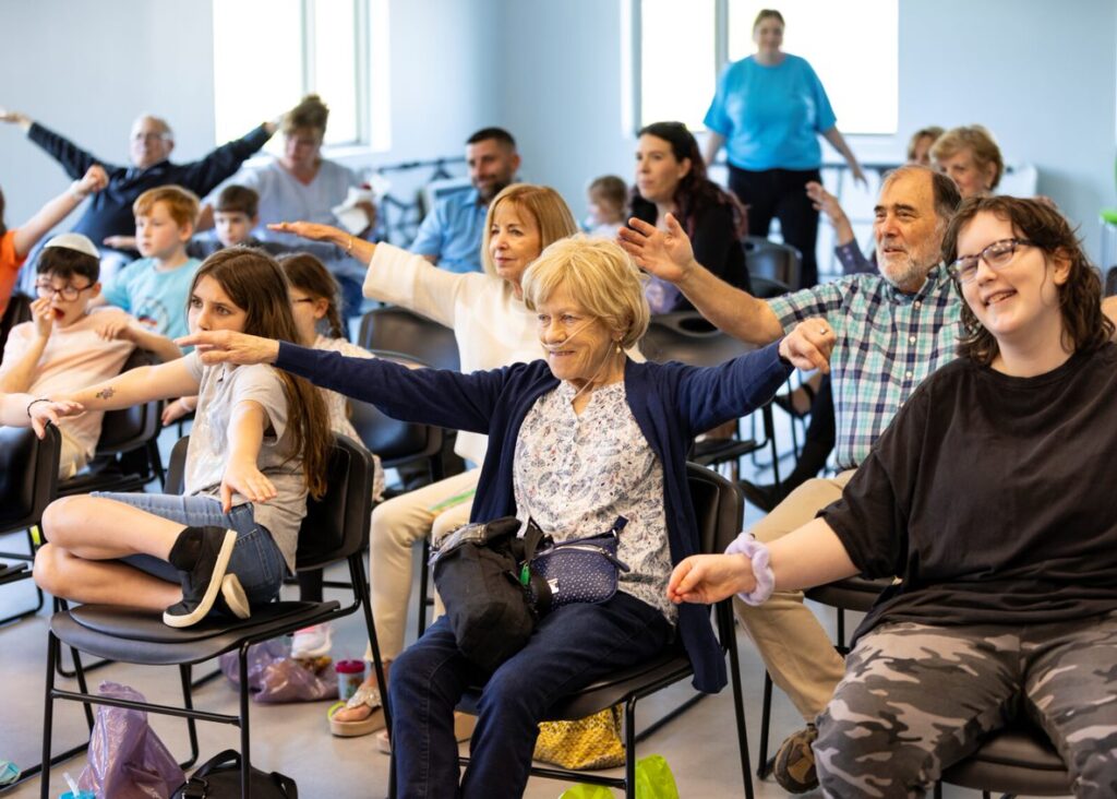 A group of seated people participate in a wellness session at Stewart's Caring Place. 