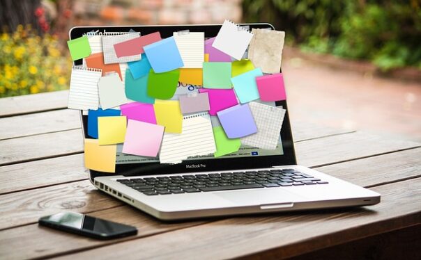 A laptop screen is covered in post-it notes of different colors.